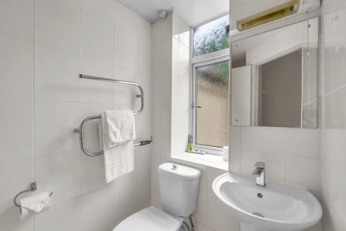 a white bathroom with a toilet and a sink at Dial House Hotel in Crowthorne