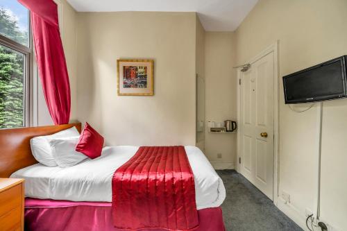 a bedroom with a bed with a red blanket at Dial House Hotel in Crowthorne