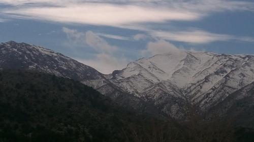 a snow covered mountain range with trees in the foreground at Neos Omalos Hotel in Omalós