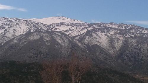 a snow covered mountain with trees in front of it at Neos Omalos Hotel in Omalós