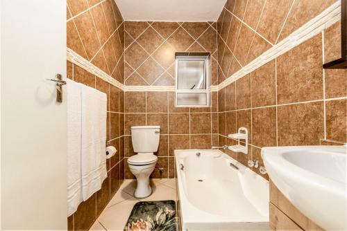 a bathroom with a tub and a toilet and a sink at II St Tropez Sandton Luxury Suites in Johannesburg