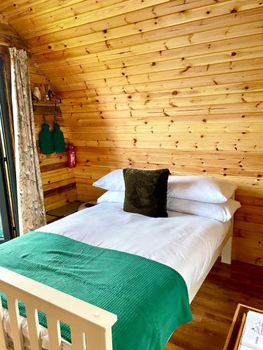 a bed in a room with a wooden wall at Cedar Pod, Clay Bank Huts in Middlesbrough