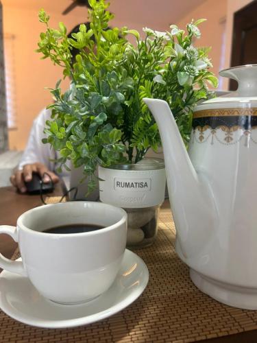 a cup of coffee and a vase with flowers on a table at RumaTisa in Teluk Intan