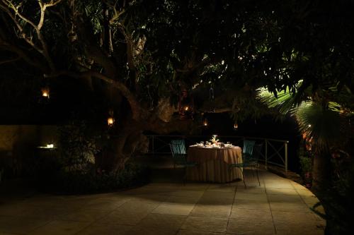 a table under a large tree at night at SaffronStays Sylvan Farms in Delmāra