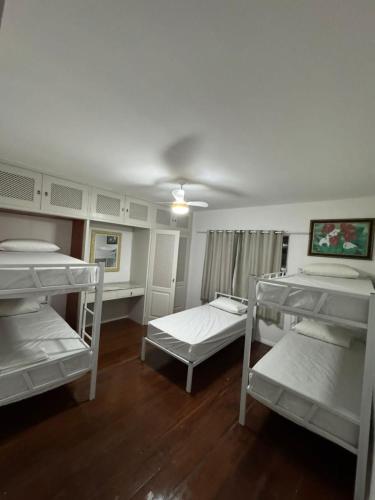 a room with three bunk beds and a ceiling at Pousada Rota do Sol in Cabo Frio