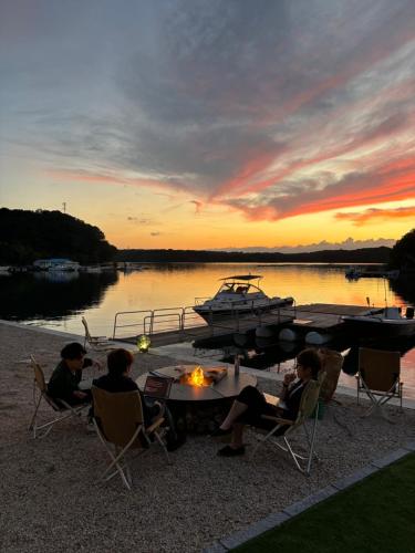 a group of people sitting around a table with a boat at 船で行く 1日1組限定の絶景宿 うみらぼ in Shima