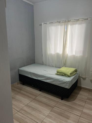 ein kleines Bett in einem Zimmer mit Fenster in der Unterkunft Centro caiçara in Praia Grande