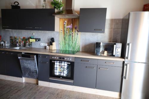 una cucina con mobili neri e un frigorifero in acciaio inossidabile di Erholung am Lehmooserhof a Gnadenwald