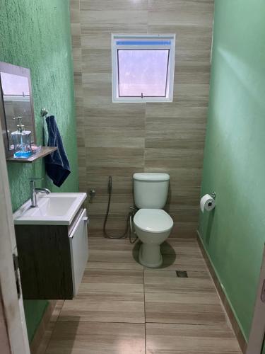 ein Badezimmer mit Toilette und Waschbecken und einem Fenster in der Unterkunft Centro caiçara in Praia Grande