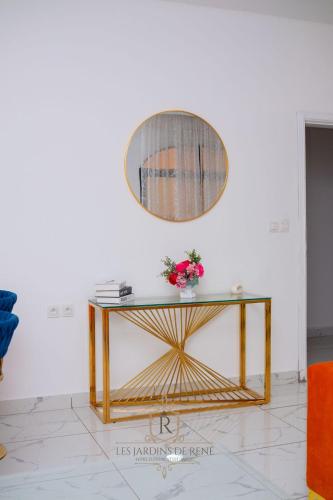 a table with a mirror and flowers on it at Les Jardins de René Hébergements in Yaoundé