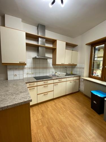 une cuisine vide avec des placards blancs et du parquet dans l'établissement Grand Maison Alsacienne, à Mommenheim