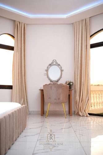 a bedroom with a chair and a mirror on the wall at Les Jardins de René Hébergements in Yaoundé
