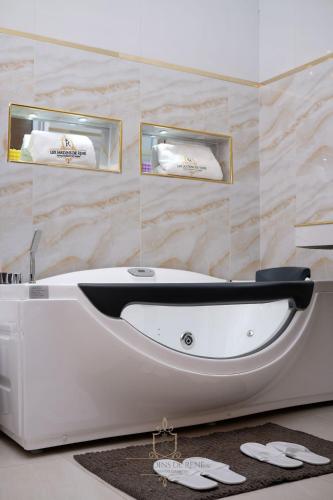 a white bath tub in a bathroom with towels at Les Jardins de René Hébergements in Yaoundé