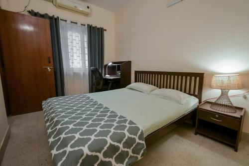 a bedroom with a bed and a table with a lamp at Snore Summore, Hostel in Koramangala in Bengaluru