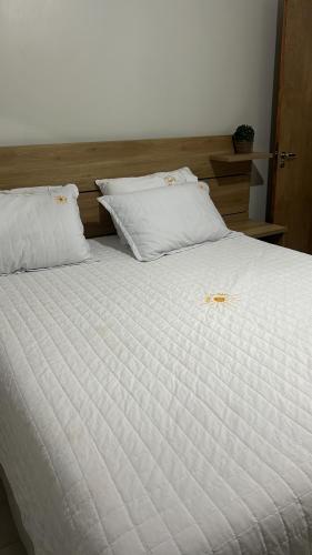 a white bed with two pillows and a star on it at Casa Riqueza da terra in Lucas do Rio Verde