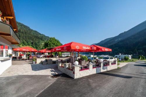 a restaurant with red umbrellas in a parking lot at Fischerhof Glinzner Hotel-Restaurant-Camping in Afritz