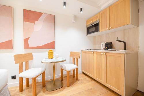 une cuisine avec des armoires en bois et une table et des chaises dans l'établissement CIA - Saint-Germain des prés, à Paris