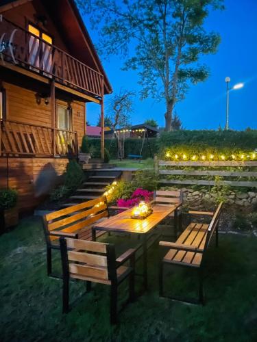 a patio with a table and benches and lights at Domek nad jeziorem in Olszyna