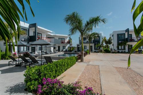 a resort with a swimming pool and palm trees and purple flowers at Genesis Residences in Meads Bay