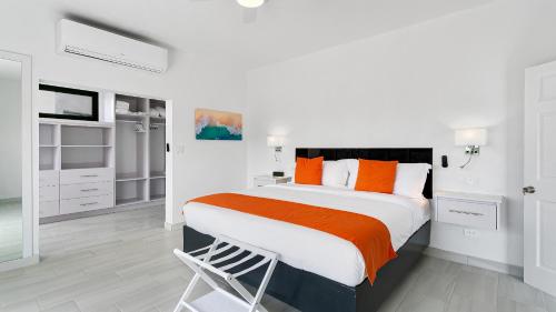 a white bedroom with a large bed with orange pillows at Genesis Residences in Meads Bay