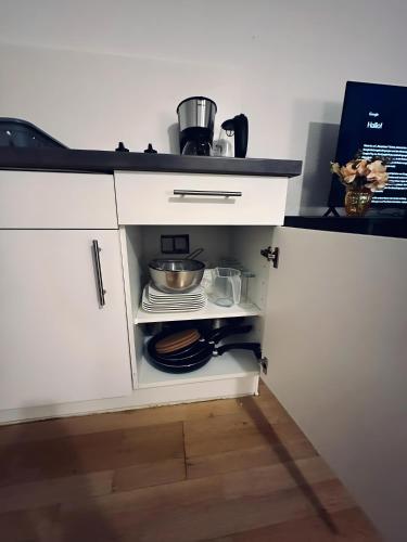 a kitchen with a white cabinet with pots and pans at sleepWELL-Horstmar Zentral & Kirchennah in Horstmar