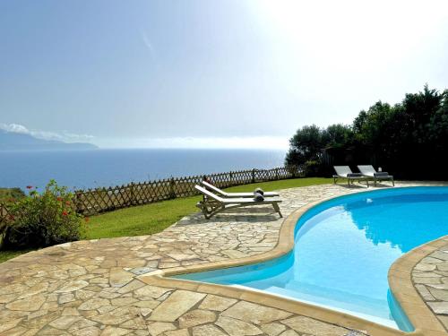 a swimming pool with a bench next to the ocean at Villa Afroditi, Spartia, Kefalonia in Kefallonia