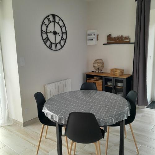 une table et des chaises dans une pièce avec une horloge au mur dans l'établissement La Grange aux Abeilles 1, à Saint-Senier-sous-Avranches