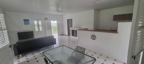 a kitchen with a glass table in the middle of a room at Haut de villa 1chambre climatisée à 3min de l'habitation Clément in Le François