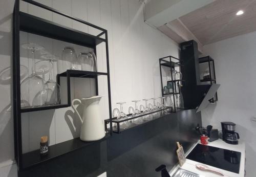 a kitchen with a counter with glasses on a shelf at Au Katalu in Pléaux