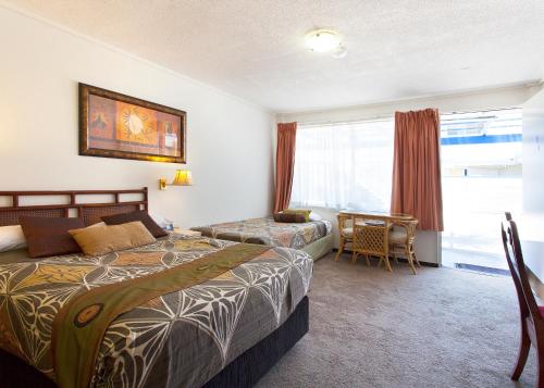 a bedroom with a bed and a desk and a window at Raceways Motel in Brisbane