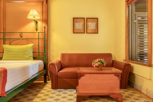 a bedroom with a bed and a couch and a table at Pung-Waan Resort & Spa in Kanchanaburi