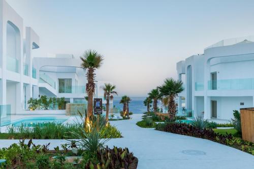a resort walkway with palm trees and the ocean at Meraki Resort Sharm El Sheikh Adults only in Sharm El Sheikh