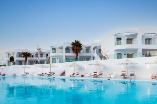 a swimming pool with chairs and umbrellas in front of a building at Meraki Resort Sharm El Sheikh Adults only in Sharm El Sheikh
