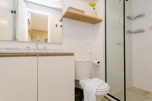 a white bathroom with a toilet and a sink at Elysia in Curitiba