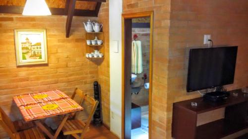 a small dining room with a table and a television at Ecos da Terra Chalés in Monte Verde