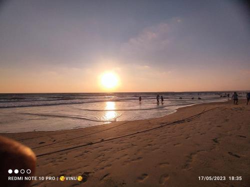 a group of people on the beach at sunset at Tarkarli beach guest house in Bhogwe