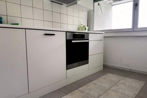 a kitchen with white cabinets and a black oven at Vully Panorama Apartment 3 Schlafzimmer nahe Bern in Zollikofen