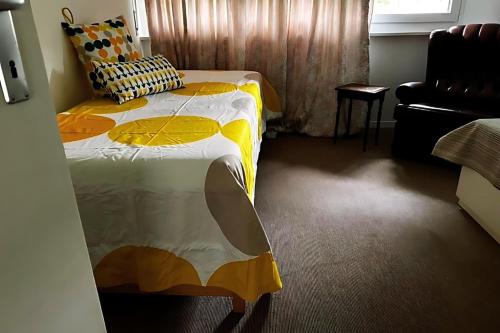 a bedroom with a bed with a yellow and white comforter at Vully Panorama Apartment 3 Schlafzimmer nahe Bern in Zollikofen