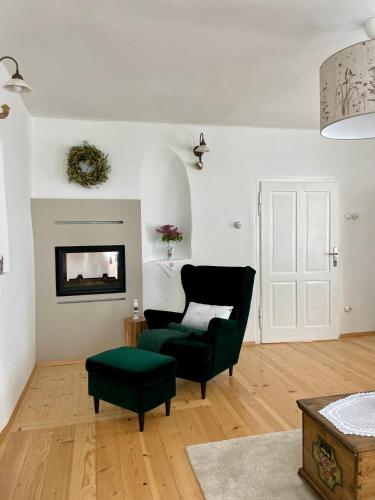 a living room with a black chair and a green ottoman at Homestead at Stefka's in Mokronog