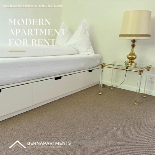 a bedroom with a bed with a lamp and a table at Vully Panorama Apartment 3 Schlafzimmer nahe Bern in Zollikofen