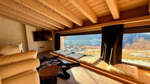 a room with a large window in a room with a couch at Lo Chalet Incantato del Maso K in Folgaria