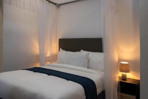 a bedroom with a bed with white sheets and curtains at Hilltop Executive Lodge in Lilongwe