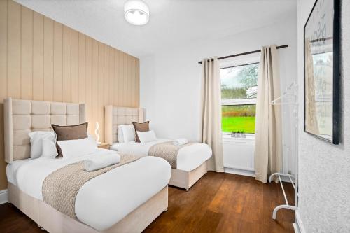 a white bedroom with two beds and a window at Stylish 3-Bedroom House - Garden - Parking - Netflix 18M in Birmingham