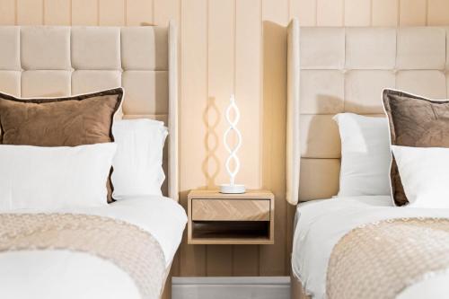 two beds with white sheets and a nightstand between them at Stylish 3-Bedroom House - Garden - Parking - Netflix 18M in Birmingham
