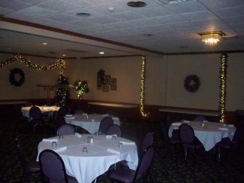 a dining room with white tables and chairs at Gladstone Inn and Suites in Jamestown
