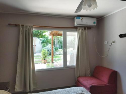 ein Schlafzimmer mit einem Fenster mit einem Stuhl und einem Bett in der Unterkunft Los Tres Soles in Mar del Plata