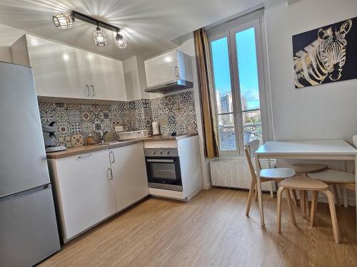 - une cuisine avec des appareils blancs, une table et des chaises dans l'établissement Nid Douillet au Bord du Canal #D, à Chelles