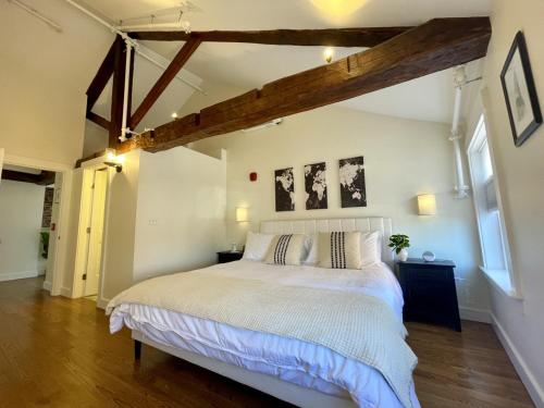 a bedroom with a large white bed with wooden beams at Penhallow Suite Downtown Portsmouth in Portsmouth