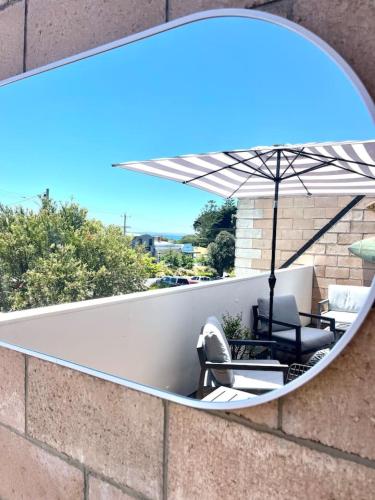 a mirror on a wall with a chair and an umbrella at Prime Portsea Pad, perfect for 2 in Portsea