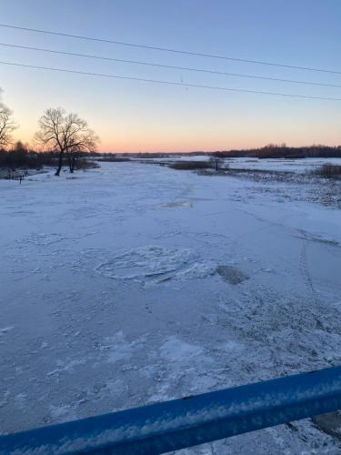 a field covered in snow with the sunset in the background at Biebrzańska Przystań 3 in Goniadz